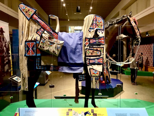 A statue of a brown horse decked out for a parade in colorful gear and lots of fringe at the Museum of the Rockies Bozeman MT