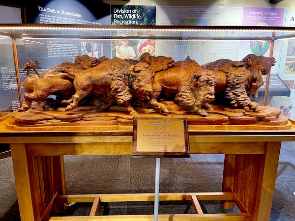 Wood carving of a bison herd/