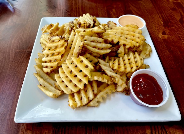 Square white plate topped with waffle fries and dipping sauce in Idaho Falls
