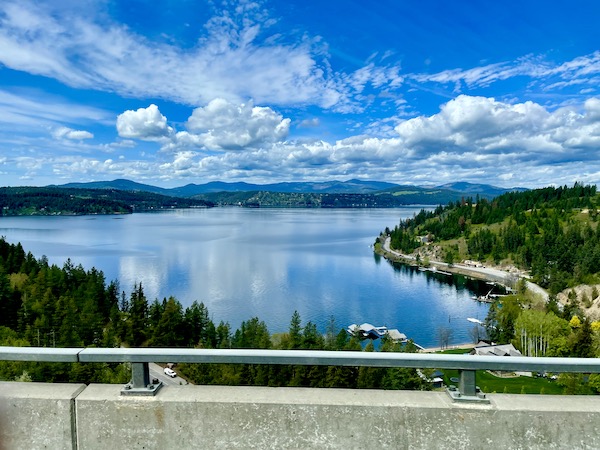 Lake surrounded by mountains and trees seen from the highway driving from Spokane WA to Coram Montana