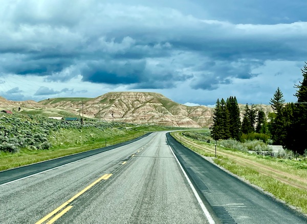 Highway with mountains that are beige stone with greenery in Dubois Wyoming