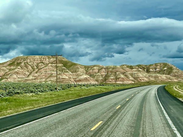 Rock mountains with a few trees and highway after Teton Mountain Range Wyoming