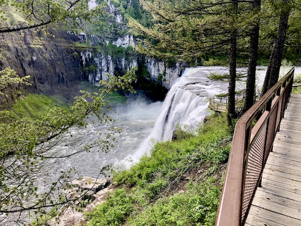 A waterfall in the woods with a boardwalk viewing platform seen while Visiting Ashton Idaho.