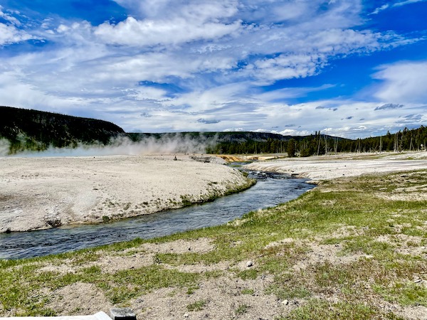 Volcanic steam rising from the ground by a river in Yellowstone National Park Wyoming