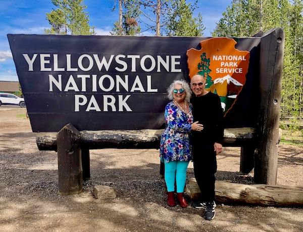 Steve and I standing by the west entrance sign to Yellowstone National Park Wyoming