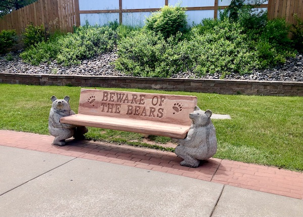 Park bench with bear sculptures and the words Beware of the Bears engraved in the seat back