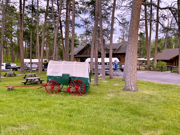 Cabins and a covered wagon, trees and lawn at Custer State Park Custer SD