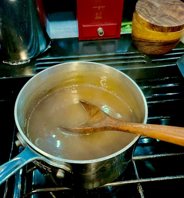 Gravy in a pot on the stove with a wooden spoon for a Happy Thanksgiving 2022!