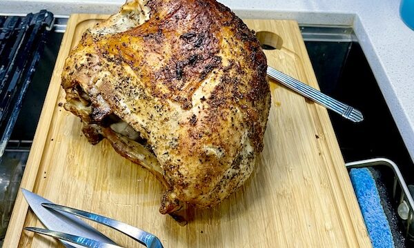 Golden brown roasted turkey breast on a cutting board with carving set for a Happy Thanksgiving 2022!
