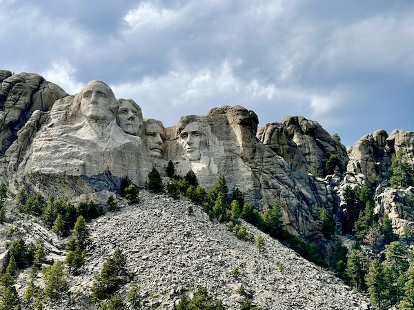 Storm clouds roll out and sun lights the faces on Mount Rushmore