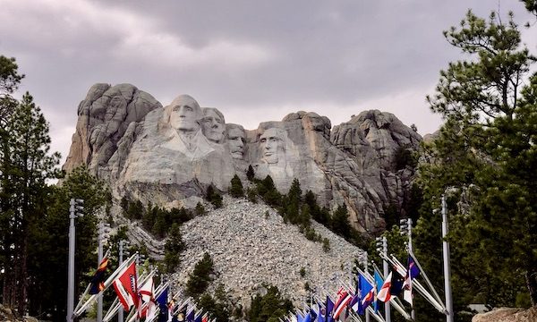 Storm clouds behind Mount Rushmore and the state flags in front.