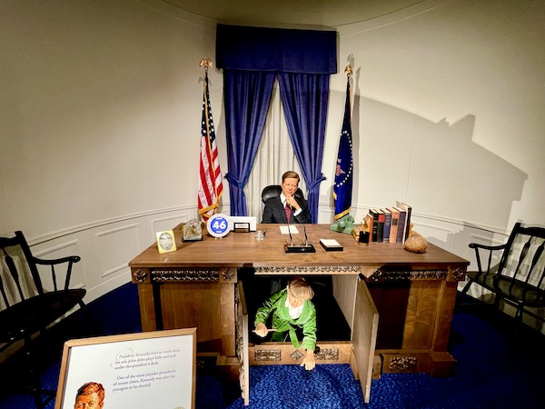 National Presidential Wax Museum Keystone SD figures of President Kennedy at his desk in the Oval Office and his little son John John hiding under it.