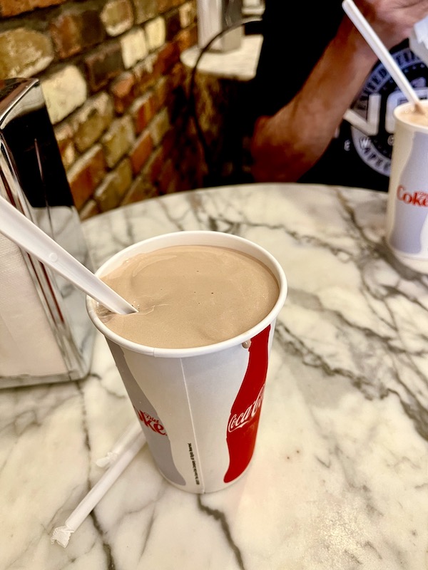 Milkshake with spoon in a red and white cup on a white and black marble table at Wall Drugs Wall South Dakota