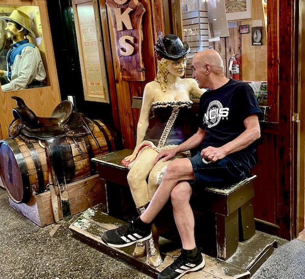 Steve is seated next to a mannequin of a saloon girl at Wall Drugs Wall South Dakota. He is being naughty with his hand on her thigh.
