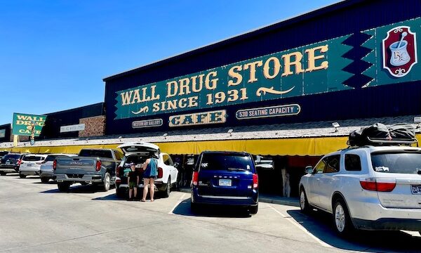 Wall Drugs Wall South Dakota is a huge western looking building with cars parked in front.