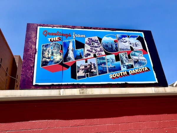 Postcard style billboard on top of a red building in Wall SD