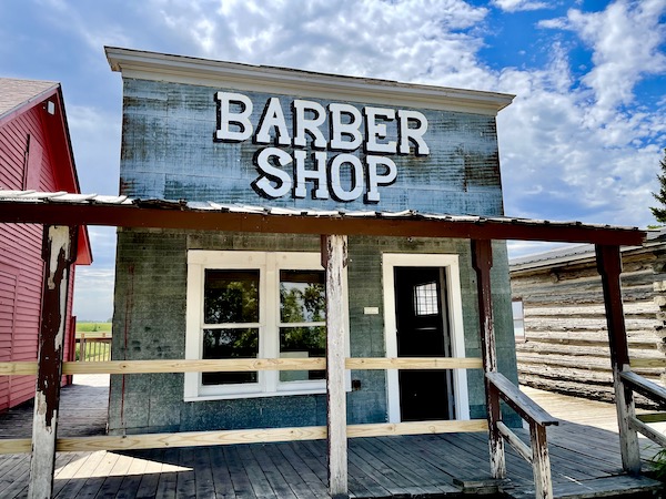 Small white washed building is Barber Shop located in Jamestown ND