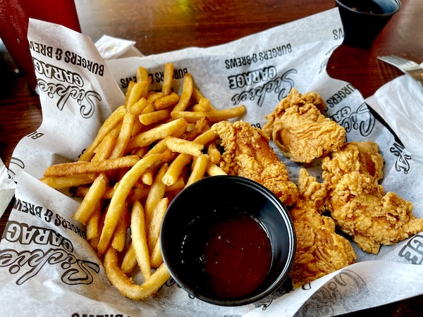 Paper lined basket filled with fries, fried chicken tenders and BBQ sauce in Fargo.