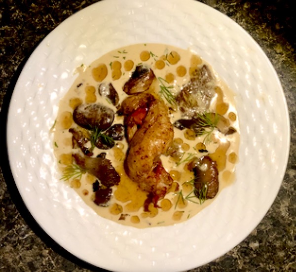 White wide rimmed plate topped with lobster tail, mushrooms and dill created by Chef Karan Puthran