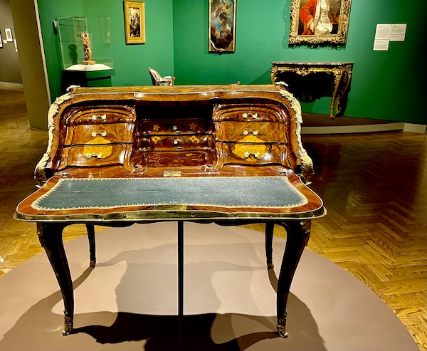 Front of an antique writing desk with light and dark wood inlay and green writing area at the Minneapolis Institute of Art