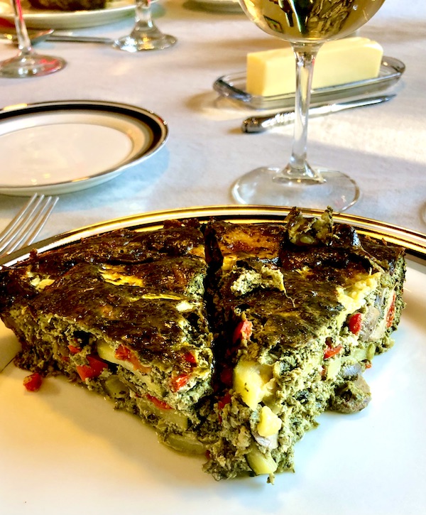 Two wedges of vegetable quiche on a white plate with black rim in Minneapolis MN