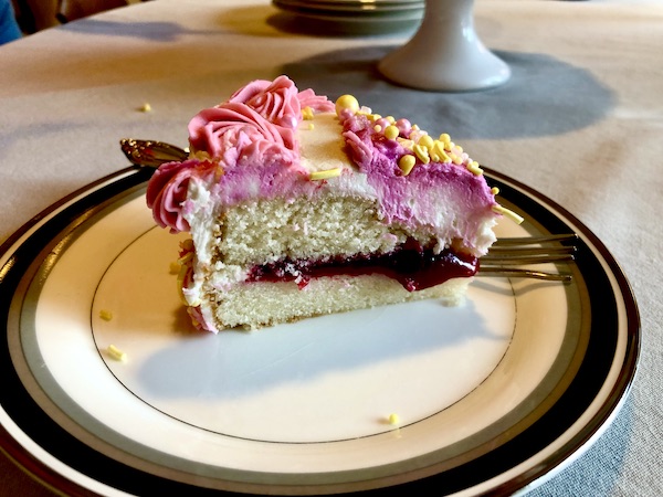 A slice of raspberry filled white cake with pink and white frosting in Minneapolis