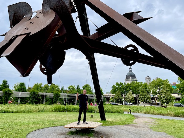 Large brown metal sculpture with wood swinging platform that Steve is standing on at the Minneapolis Sculpture Garden Minnesota