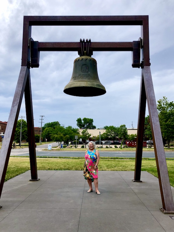 Woman in print dress standing under a bell sculpture at the Minneapolis Sculpture Garden Minnesota