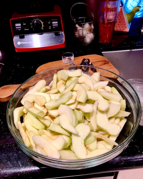 Glass bowl filling with peeled sliced apples for Candied Apple Walnut Pie