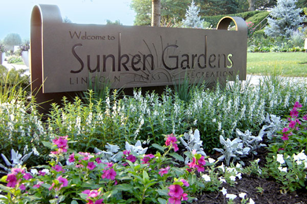A tan wall welcoming you to Sunken Gardens Lincoln Nebraska.