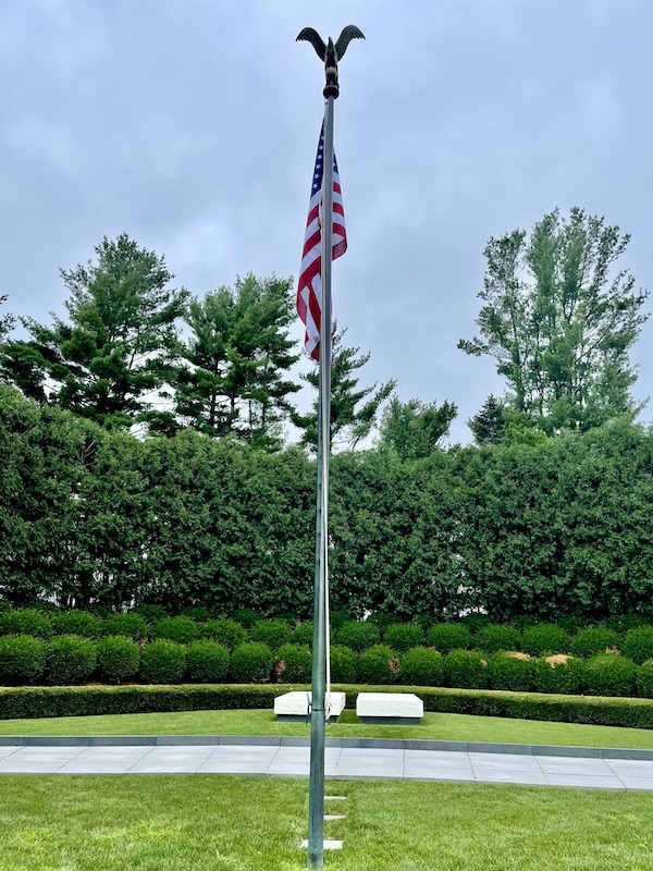 Flagpole with American Flag with eagle on top and two white rectangular grave markers at the Herbert Hoover National Historic Site Iowa