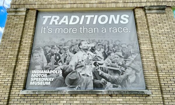 Black and white mural of a race winner drinking milk from a glass bottle at Back Home Again mural at Indianapolis Speedway Indianapolis Indiana with Indy cars.