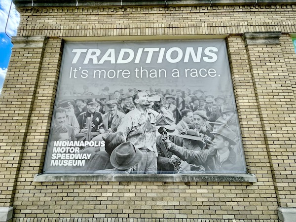 Black and white mural of a race winner drinking milk from a glass bottle at Back Home Again mural at Indianapolis Speedway Indianapolis Indiana with Indy cars.