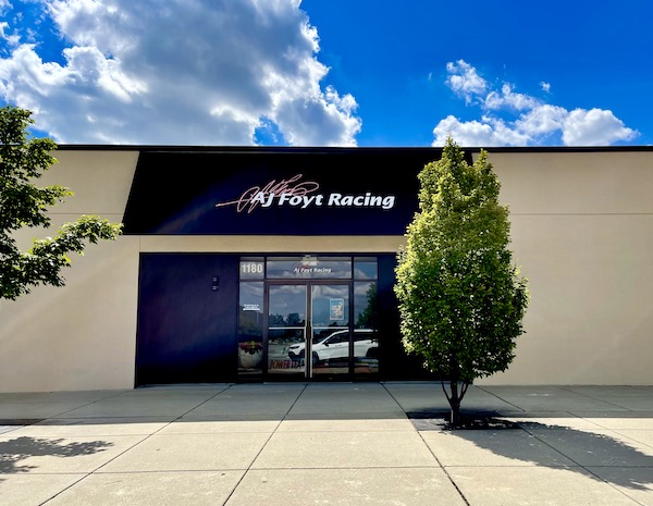 Beige and black storefront for AJ Foyt Racing at Back Home Again mural at Indianapolis Speedway Indiana with Indy cars.
