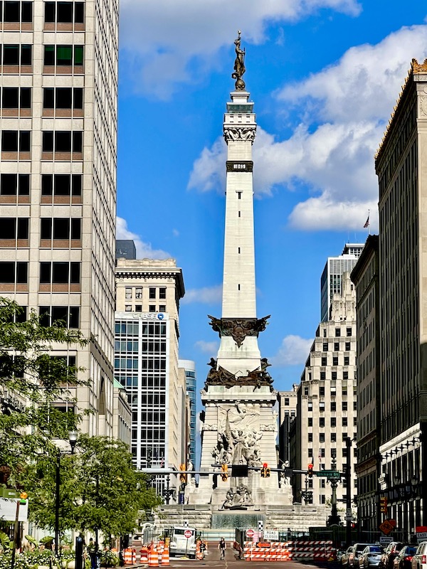 White obelisk with weathered bronze adornment in downtown Indianapolis