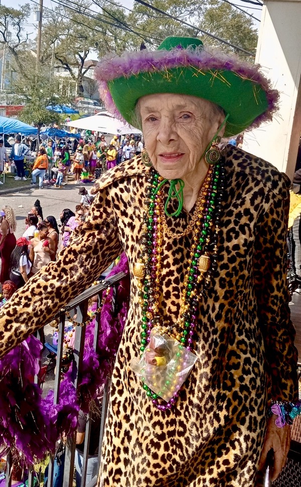 Woman in leopard outfit, green hat and lots of Mardi Gras beads