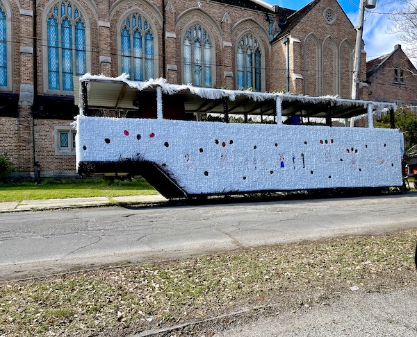 A white glittery Mardi Gras float parked in front of a brick building for Mardi Gras 2023 New Orleans