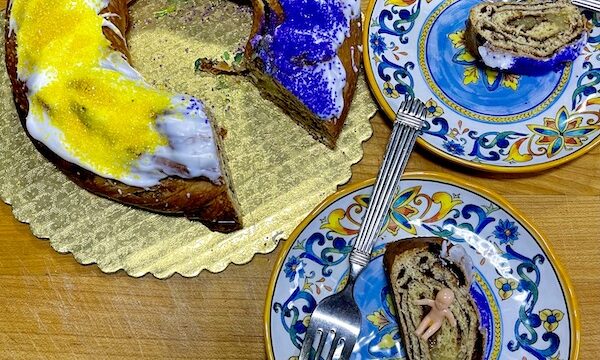 Purple, Gold and green circular cake with wedge missing. Two plates with slices of cake enjoyed for Mardi Gras 2023 New Orleans