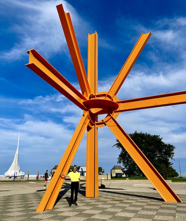 Orange metal asterisk sculpture with Steve in yellow shirt at Milwaukee Art Museum Wisconsin
