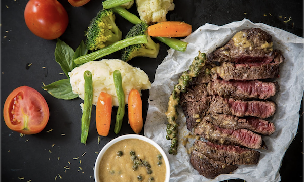 Sliced cooked steak with carrots, cauliflower and a small bowl of sauce from Secret to Cooking Delicious Meat