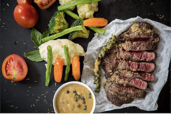 Sliced cooked steak with carrots, cauliflower and a small bowl of sauce from Secret to Cooking Delicious Meat