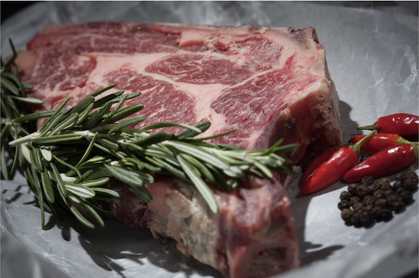 Raw rib eye steak with rosemary and red chile peppers from Secret to Cooking Delicious Meat
