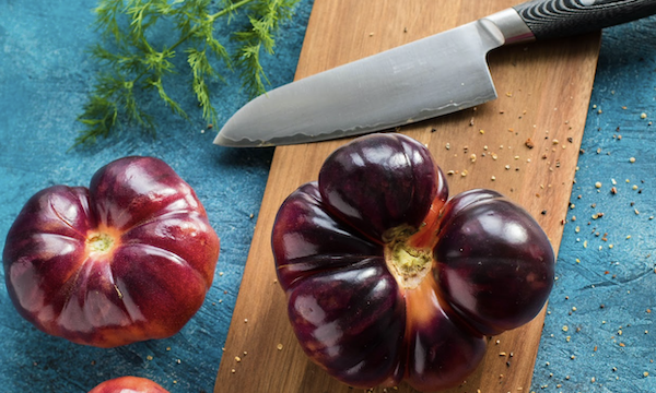 Cutting board with chef knife and heirloom tomatoes inspire e ways to improve your cooking skills today.