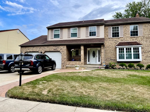 Large single brick house with 2 car garage, porch and brown roof, another of our houses in NE America