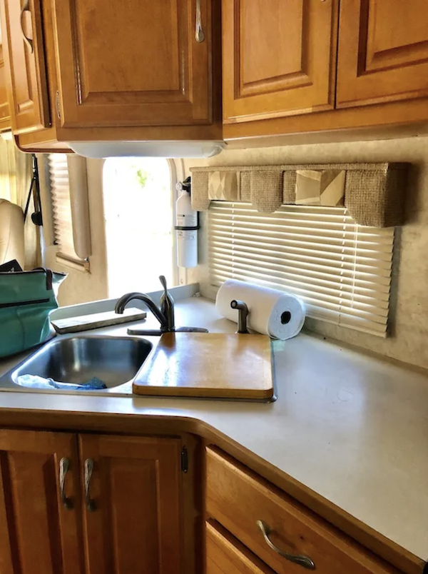 An RV kitchen with beige walls and counters, wood cabinets from How to Put the Love Back Into Cooking