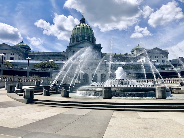 Circular fountain with step to it is in front of the The beautiful Pennsylvania State Capitol in Harrisburg
