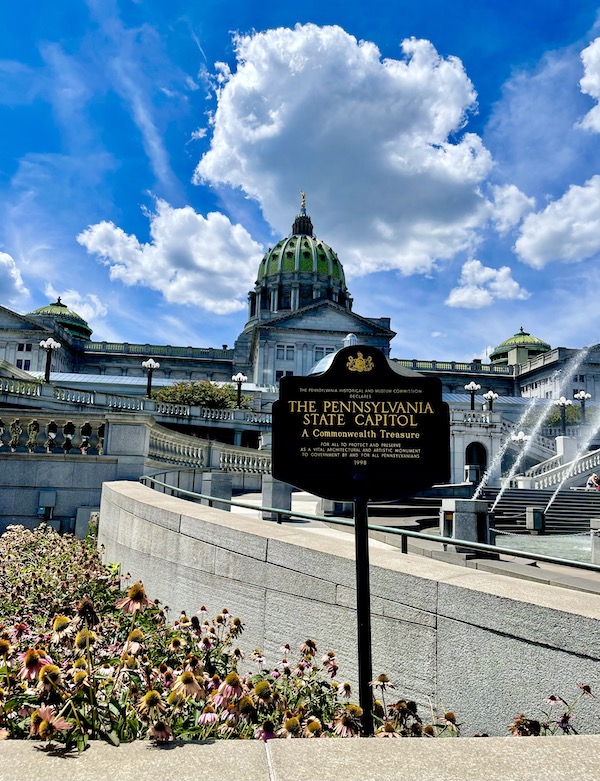 Black and gold sign in front of the The beautiful Pennsylvania State Capitol building in Harrisburg