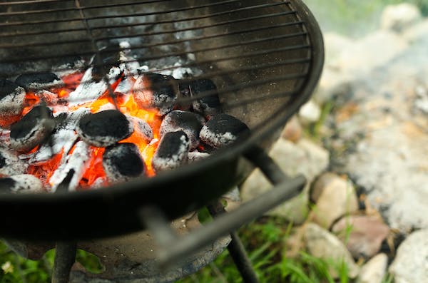 A black round grill with burning charcoal is one suggestion for The Perfect Backyard BBQ