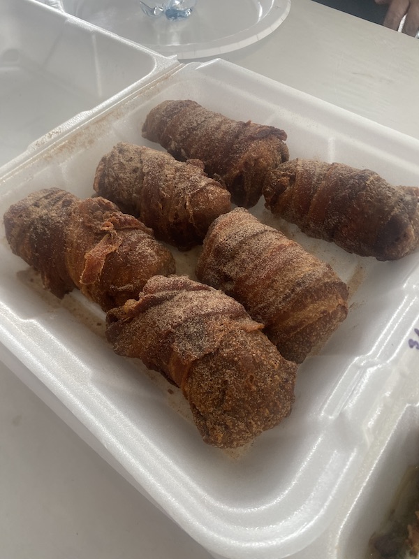 Styrofoam clamshell holding bacon wrapped egg rolls at Hogs For The Cause NOLA