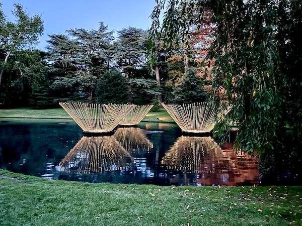 Lit up colorful trio of floating sculptures in a pond at The nighttime spectacle Light: Installations by Bruce Munro opens June 30 at Longwood Gardens. Created by English/Australian artist Bruce Munro, Light features eight installations, spanning indoors and outdoors. Highlights include the luminous Field of Light featuring 18,000 illuminated bulbs stretching across the landscape, a flamboyance of 1,000 flamingoes wading near the Chimes Tower, and C-scales, a shimmering canvas of 8,960 CDs in the Exhibition Hall that reflect colorful projections inspired by Longwood’s water gardens.